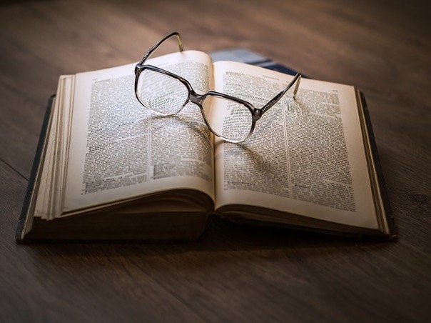 Open old textbook with glasses on it