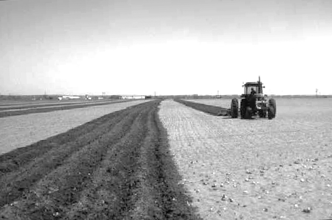 A tractor pulls a plow through a field to add ridges and increase surface roughness of the soil.