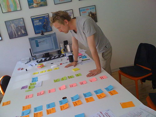A man laying out Post-It notes for planning his website. 