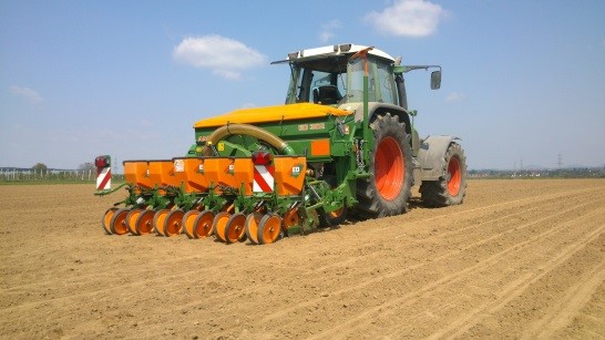 A tractor pulling a precision seeder in a field.