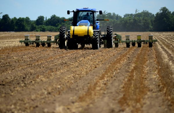 Un tractor con un accesorio de sembradora que siembra soja en un campo.