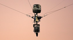 A skycam with four taut cables attached to it, keeping it suspended in midair.