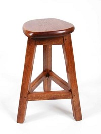 A wooden stool with a round seat on 3 legs, with each leg being connected to the two others by a single horizonal beam.