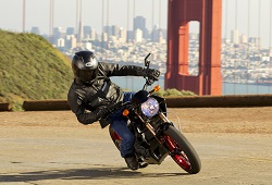 Vista frontal de un motociclista con cascos inclinado a su derecha para realizar un giro a la derecha.