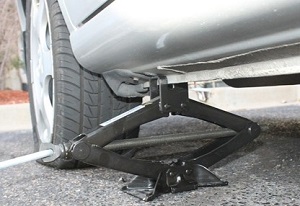 A scissor jack being used to raise or lower a car.