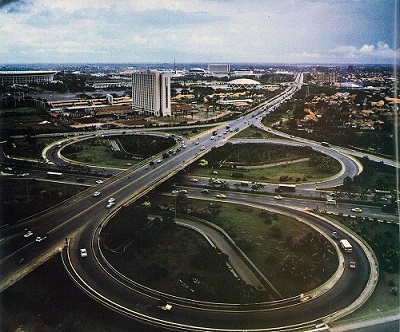 A cloverleaf interchange on a highway, being traveled by a number of cars.