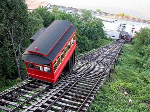 A cable car filled with passengers travels up a steep hillside.