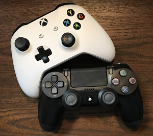 Two video game controllers, one black and one white, on a wooden table.