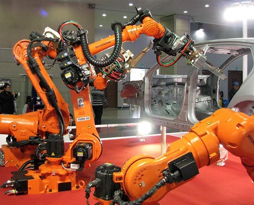 A group of robotic arms work on assembling the skeleton of a vehicle.