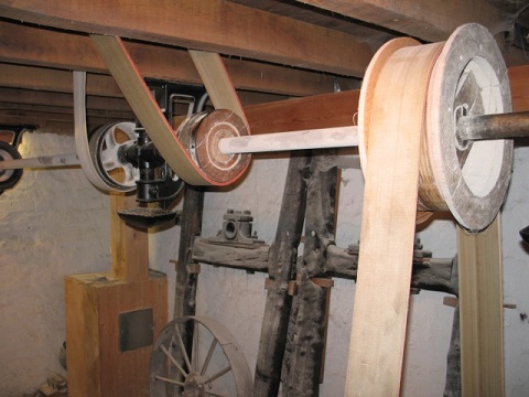 Un eje de transmisión de molino, que sostiene varias poleas conectadas a otras poleas y mecanismos por correas.