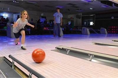 A girl in a bowling alley releases a ball down the lane.